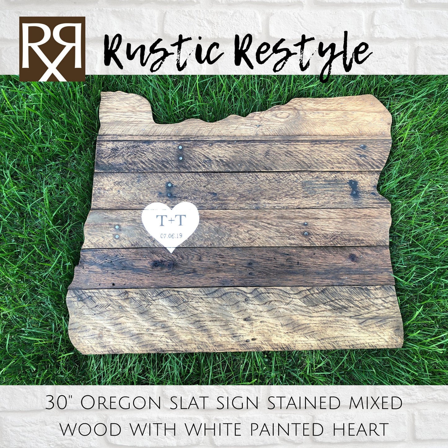wood sign shaped like Oregon, old dark worn boards with nails laying in the green grass with a  White heart painted in the center with personalization t + t