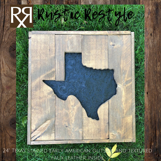 Large square wood sign with a texas shape cut out of the middle laying flat in the grass. The center Texas is recessed in and covered in faux black tooled leather.