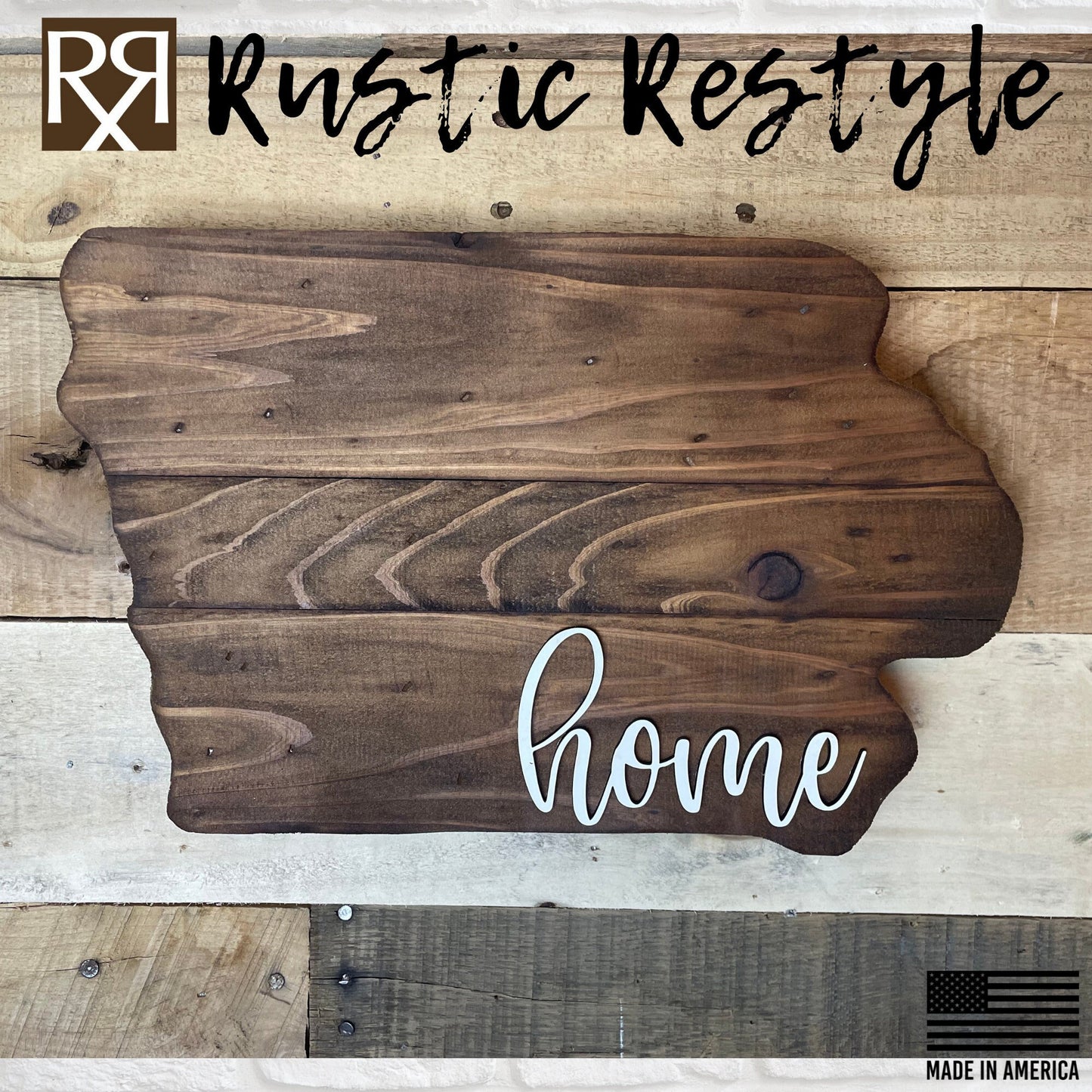 Iowa shaped wood sign with dark planks.
Script font white word "home" in the bottom right corner. The sign is hanging on a wood pallet plank wall.