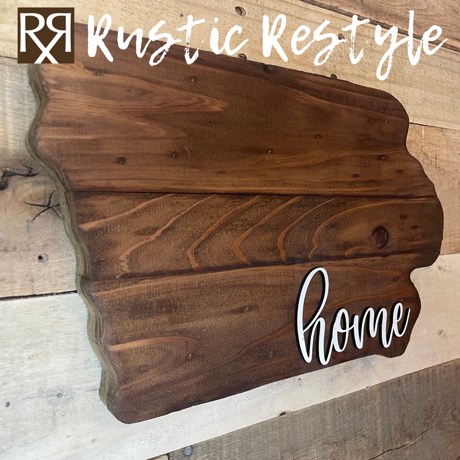 A side angle view of iowa shaped wood sign with dark planks.
Script font white word "home" in the bottom right corner. The sign is hanging on a wood pallet plank wall.
