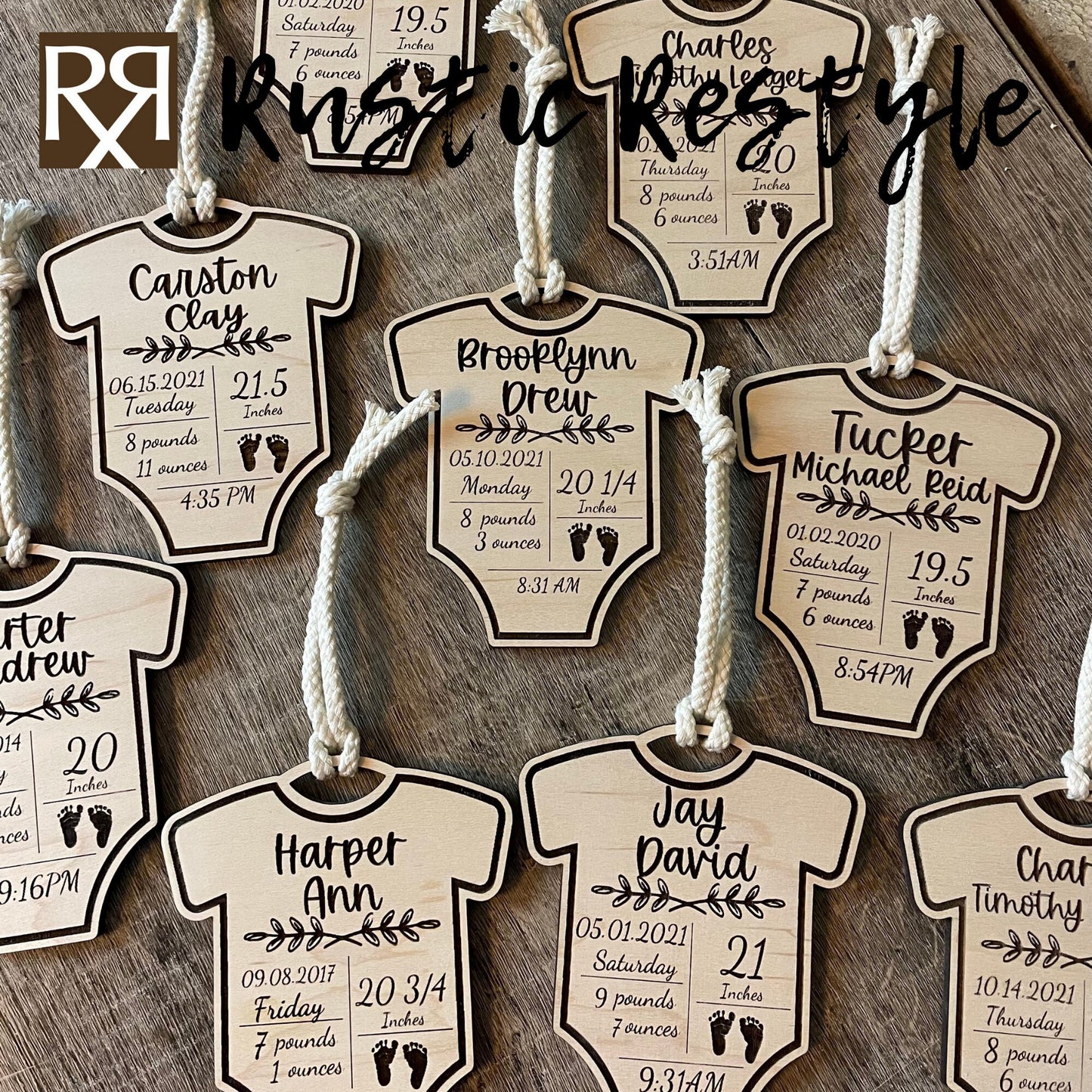 9 natural wooden ornaments shaped like baby onesies and hung by white cotton braided strings laying flat on a table. These items are engraved with each baby's name and birth stats.