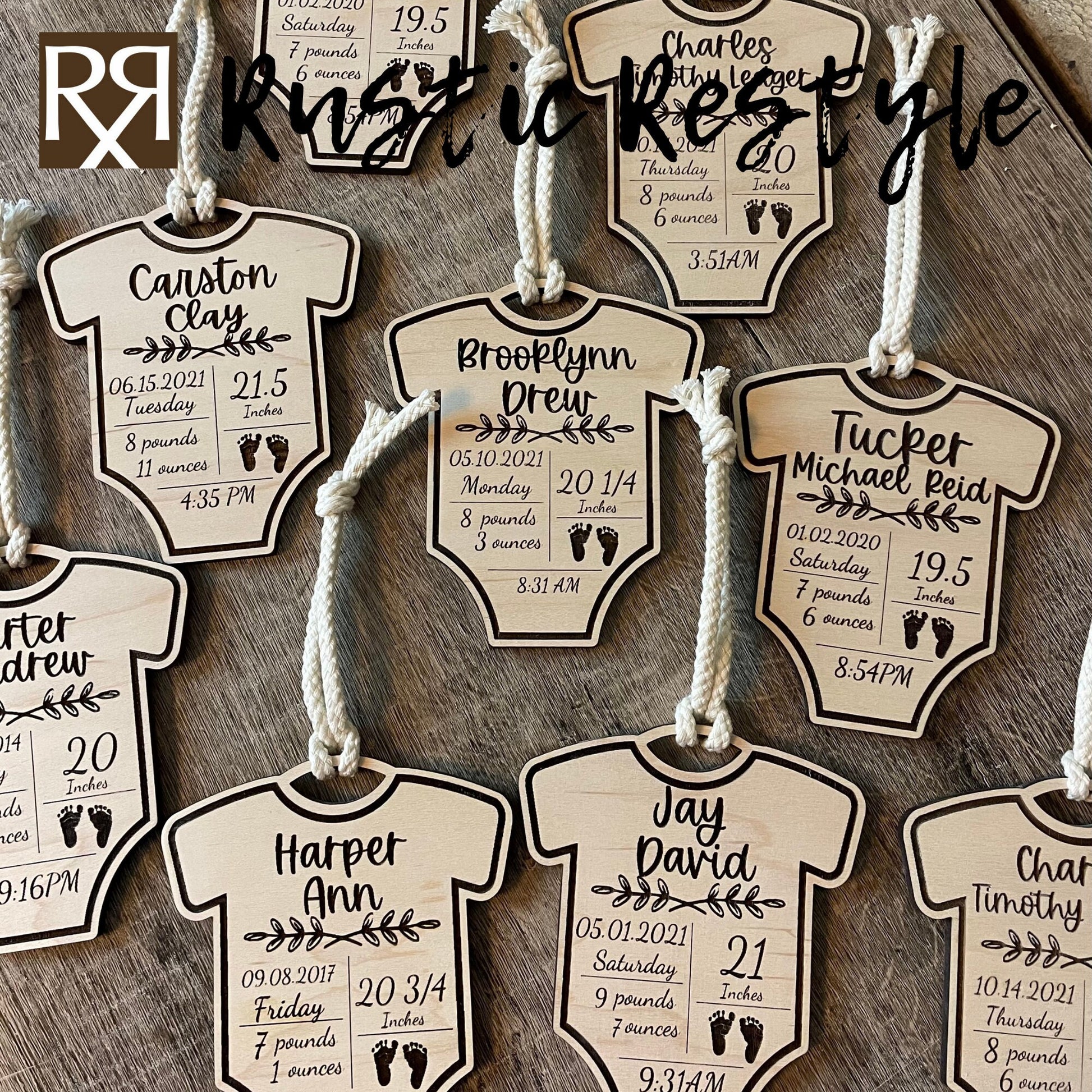 9 natural wooden ornaments shaped like baby onesies and hung by white cotton braided strings laying flat on a table. These items are engraved with each baby's name and birth stats.