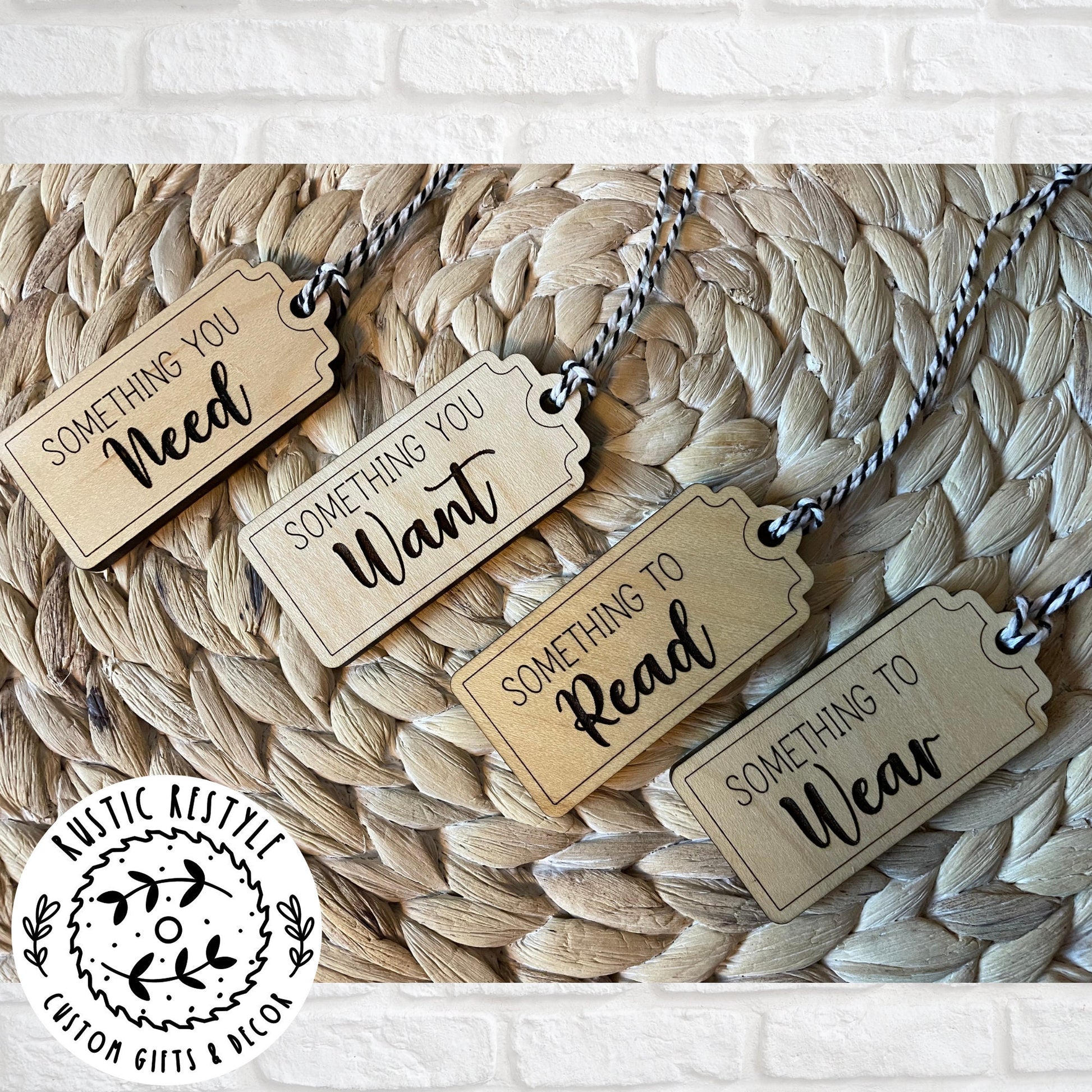 4 Christmas gift tags laying on a woven placemat. First tag says Something you Need. Second tag says Something you Want. Third tag says Something you Read and the last tag says something you Wear. Each tag has a black and white bakers twine string.