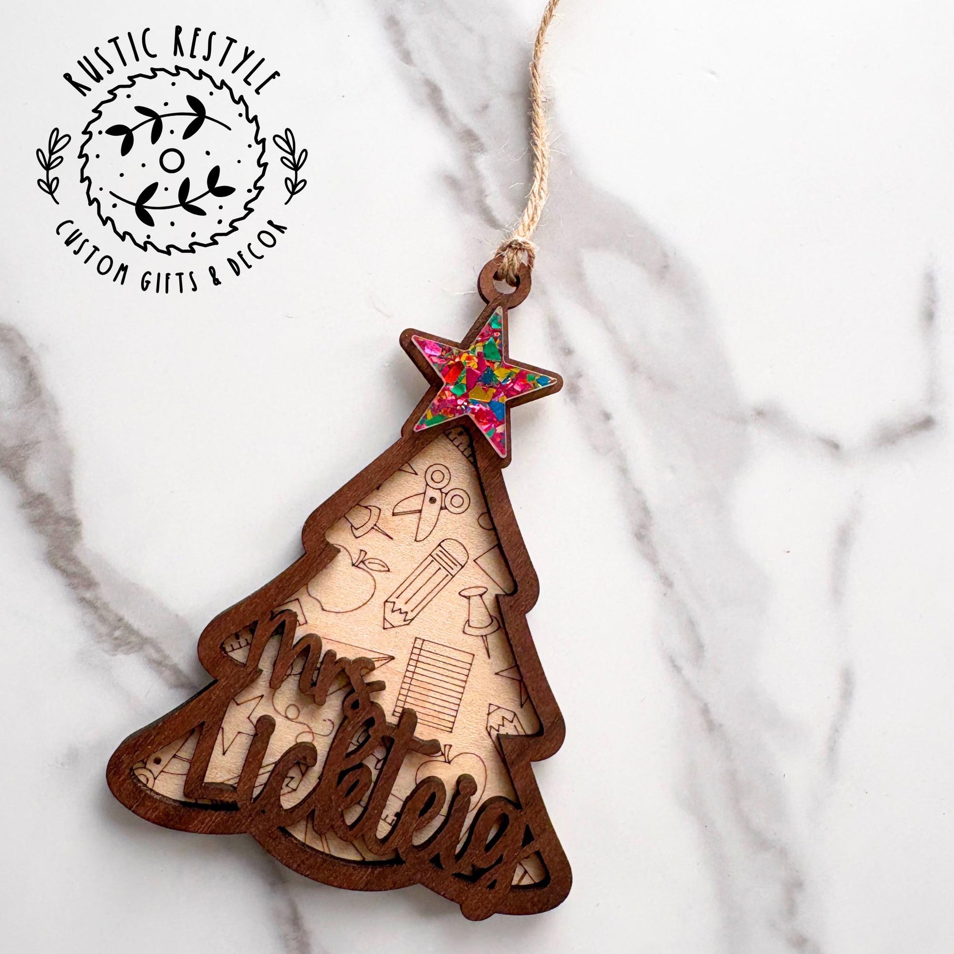Wooden Christmas tree ornament with engraved school icons and a personalized teacher name, topped with a colorful star and twine hanger.