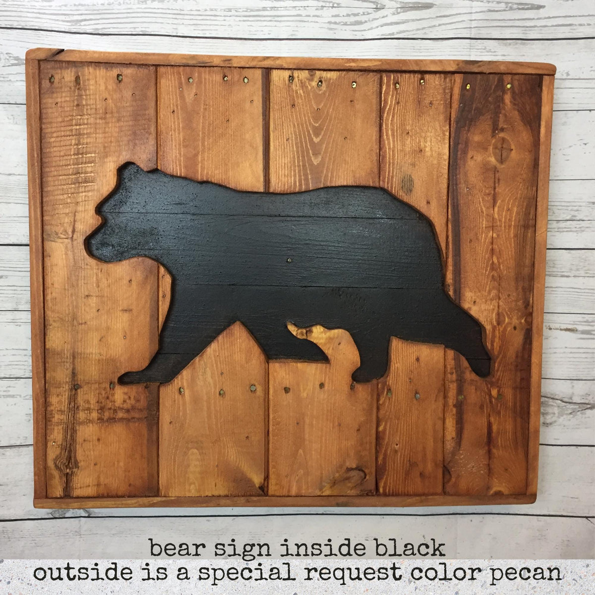 A wooden sign featuring a black silhouette of a bear, mounted on a wooden background.