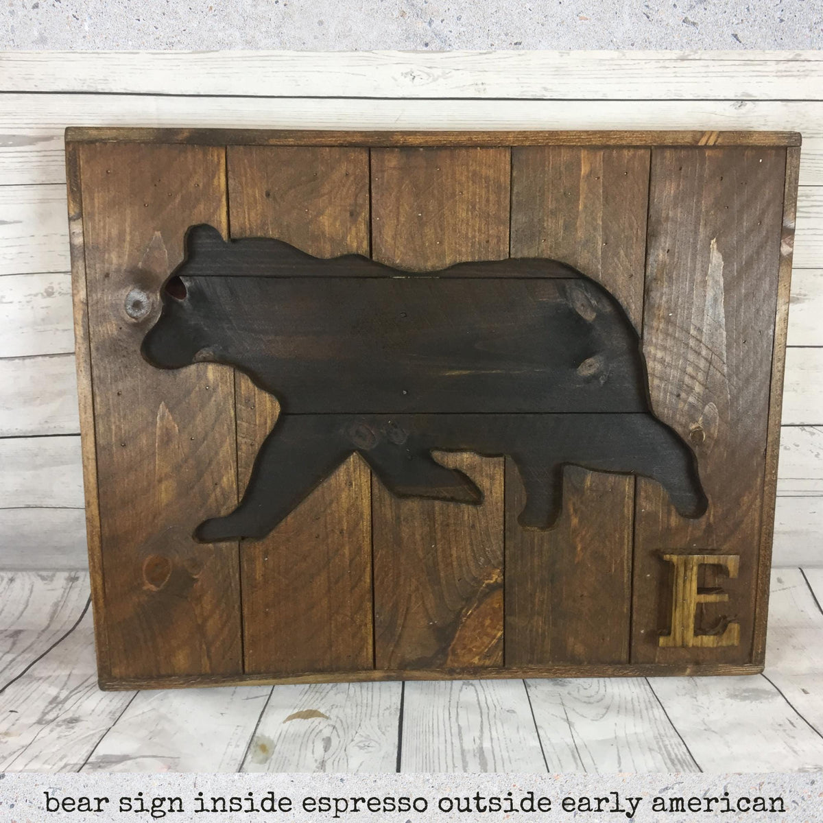 A wooden sign featuring a silhouette of a bear, with the letter "E" below it.