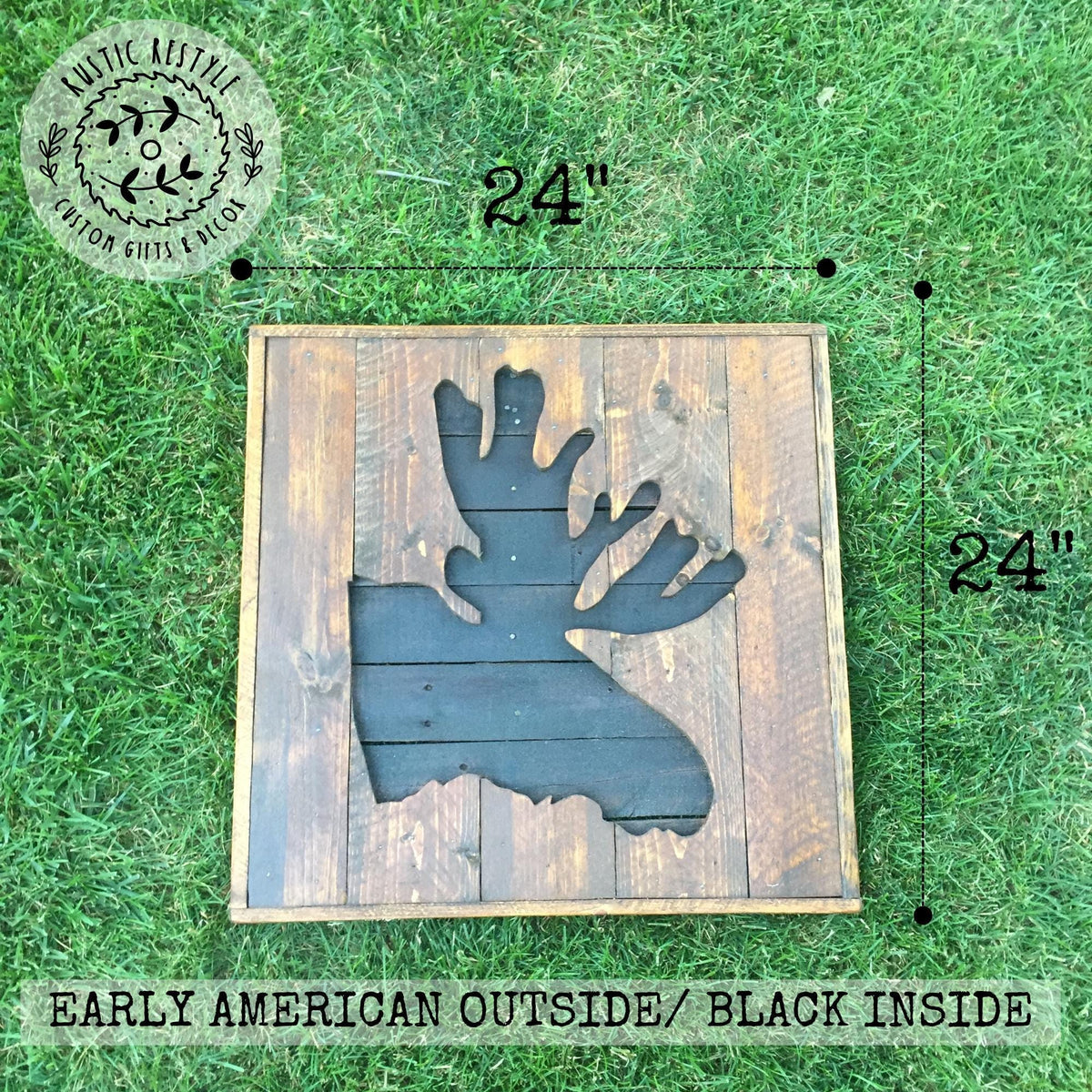 a wooden sign with a moose silhouette cut out, placed on a grassy surface.