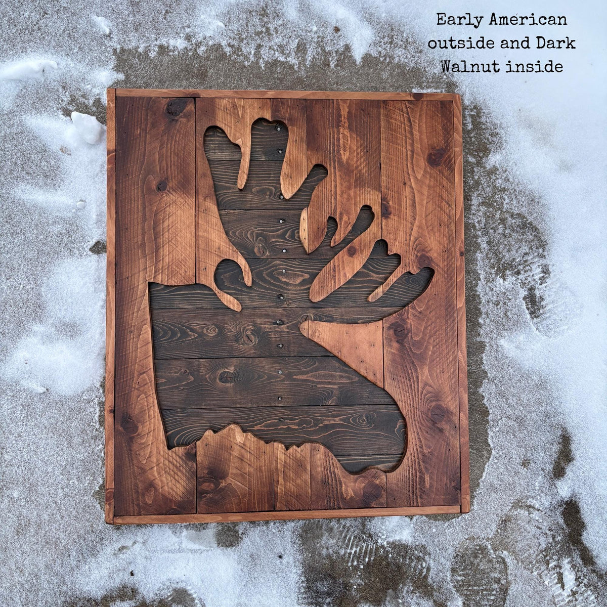 a wooden cutout of a moose head, which is mounted on a wooden board.