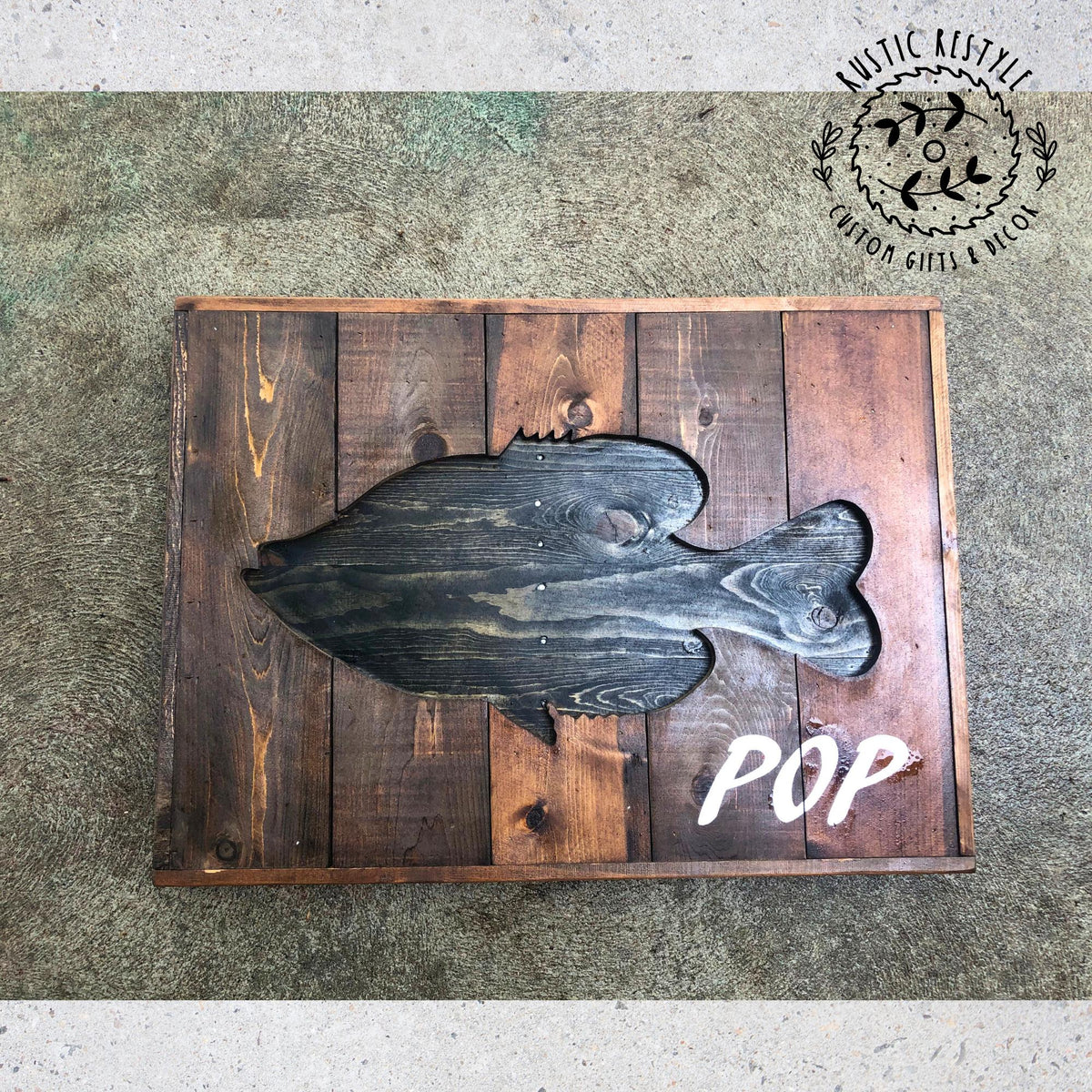 a wooden sign with a fish cutout, placed on a wooden surface.
