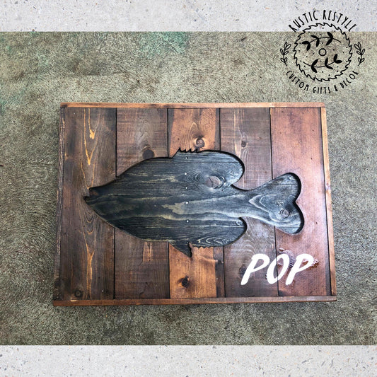 a wooden sign with a fish cutout, placed on a wooden surface.