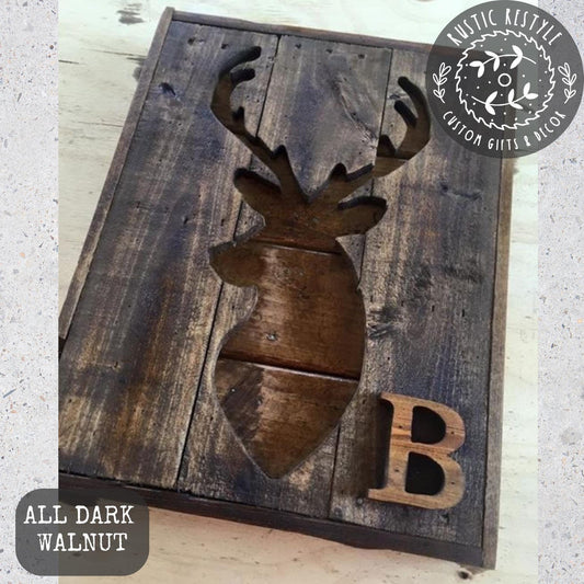 A wooden sign with a cutout of a deer head and the letter "B" below it, placed on a wooden surface.