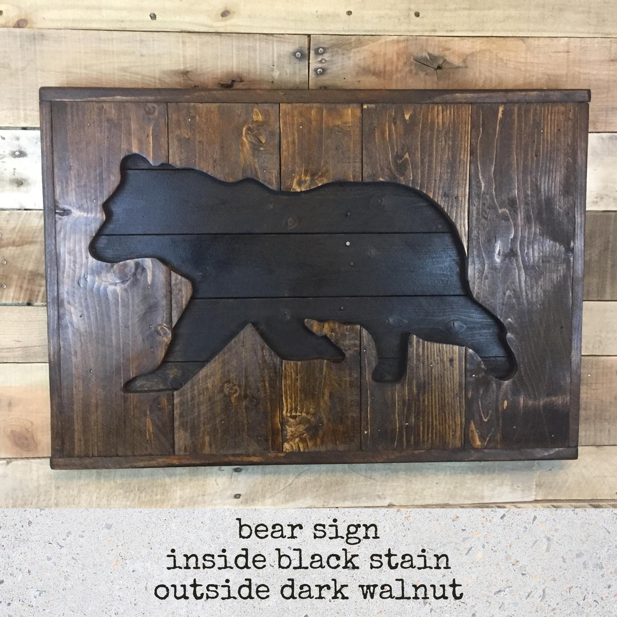 A wooden bear sign is mounted on a wooden wall, featuring a black silhouette of a bear carved from wooden planks.