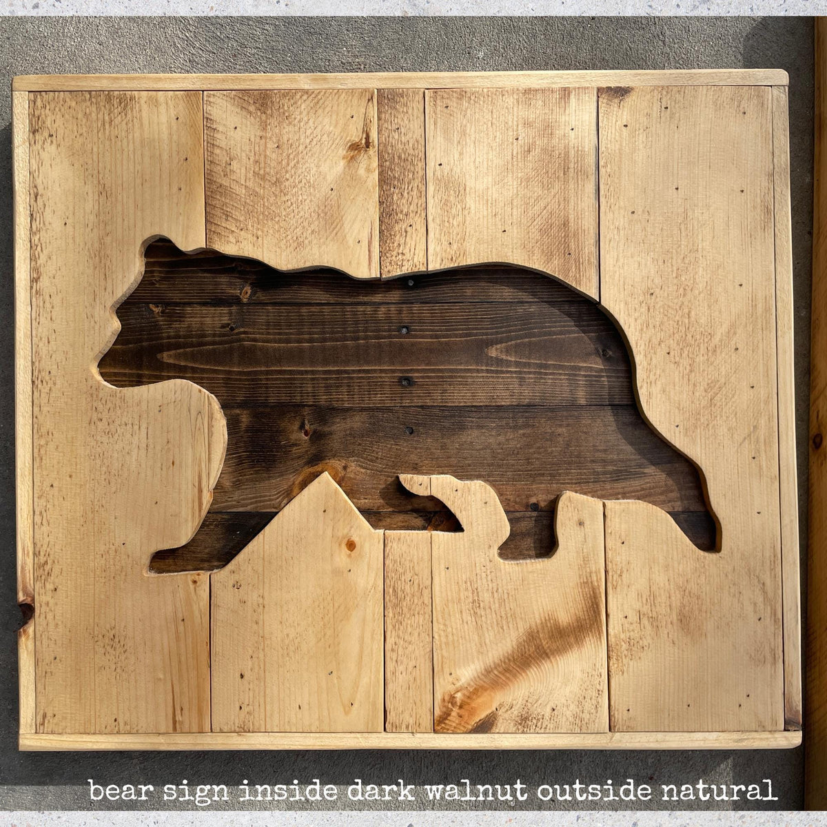 a wooden sign with a cutout of a bear shape, made from wooden planks.