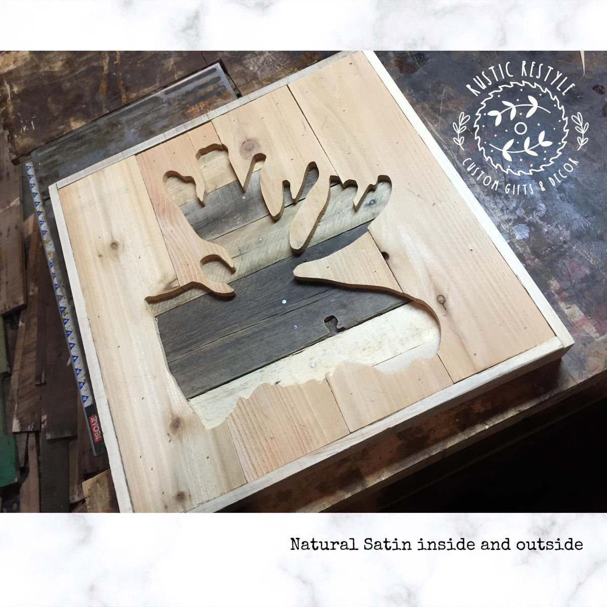 a wooden sign with a cutout design of a moose, made from wooden planks. The sign is placed on a wooden surface, and there is a text overlay that reads "Natural Satin inside and outside".