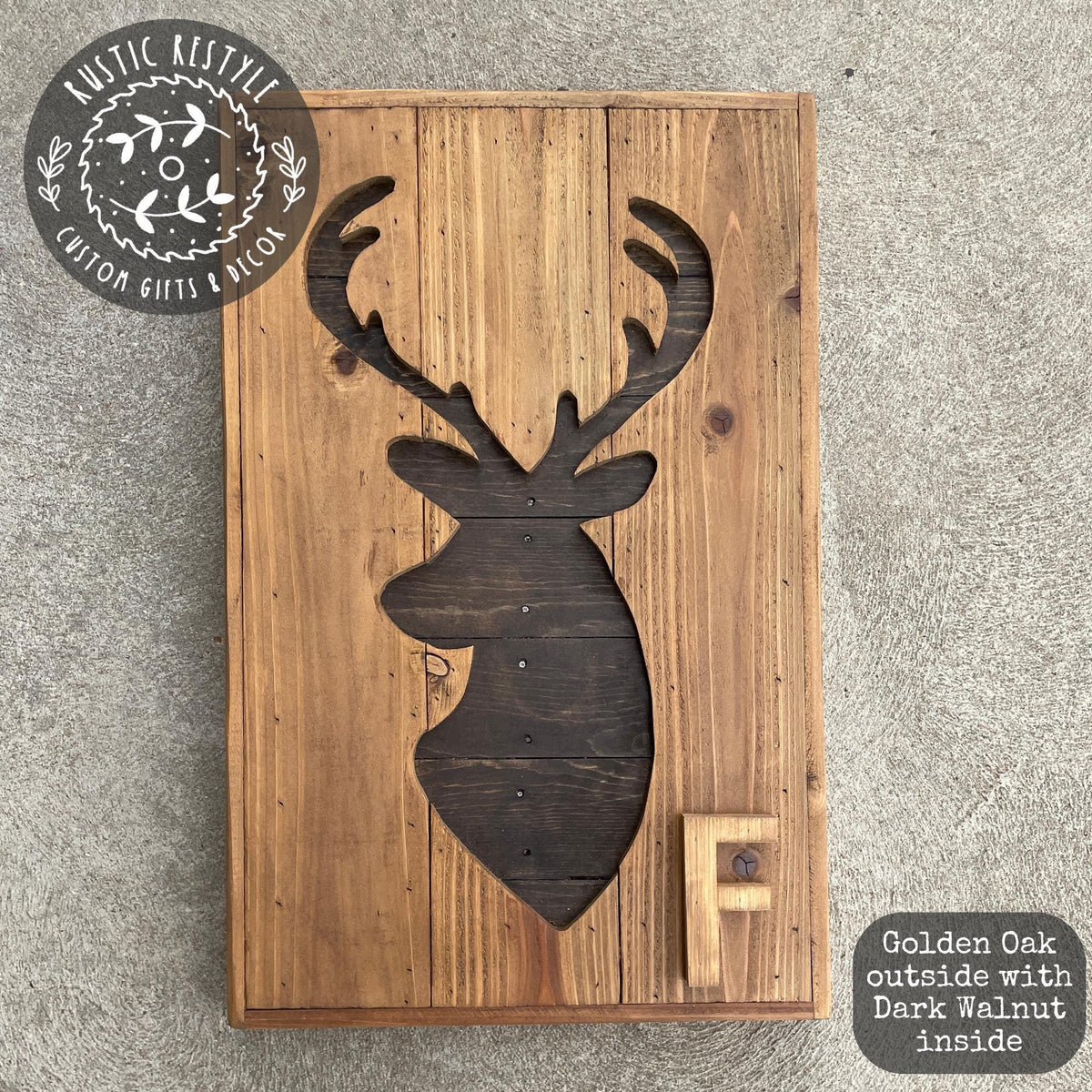 a wooden deer head cutout on a wooden board, with the letter "F" carved into the deer's head.