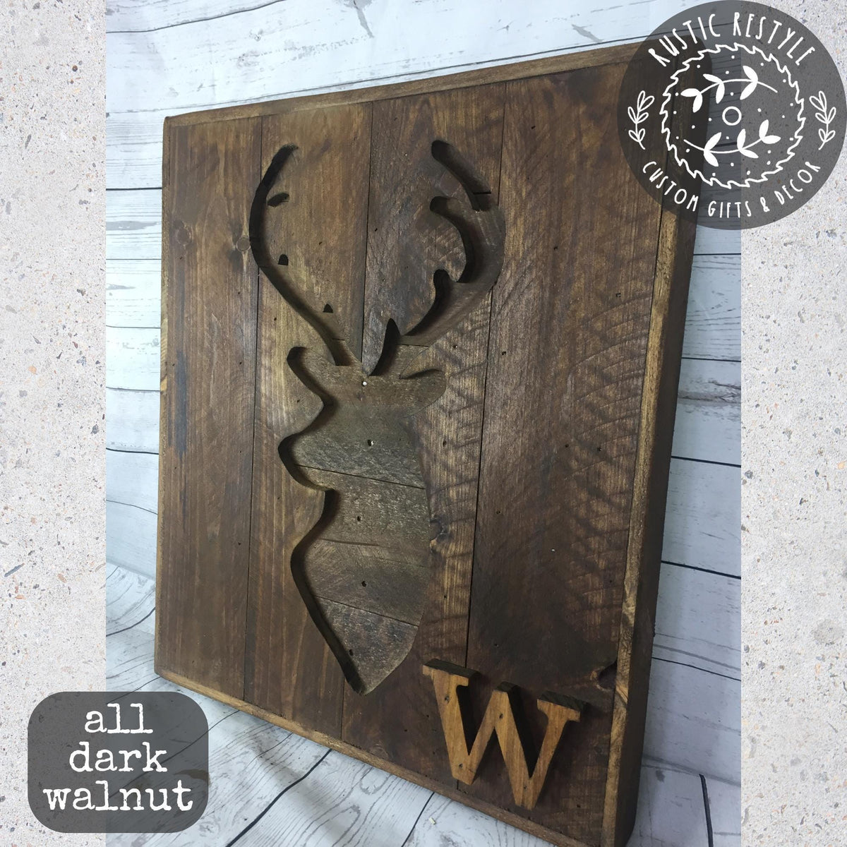 A wooden sign with a carved deer head and the letter "W" on it, placed on a wooden surface.