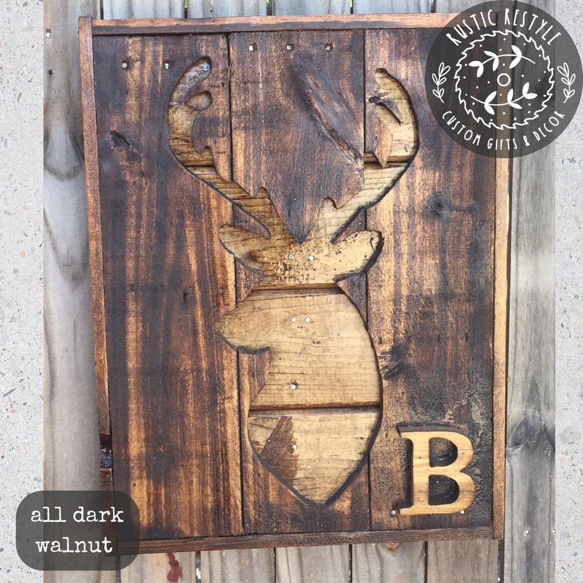 A wooden sign with a carved deer head and the letter "B" on it, mounted on a wooden wall.