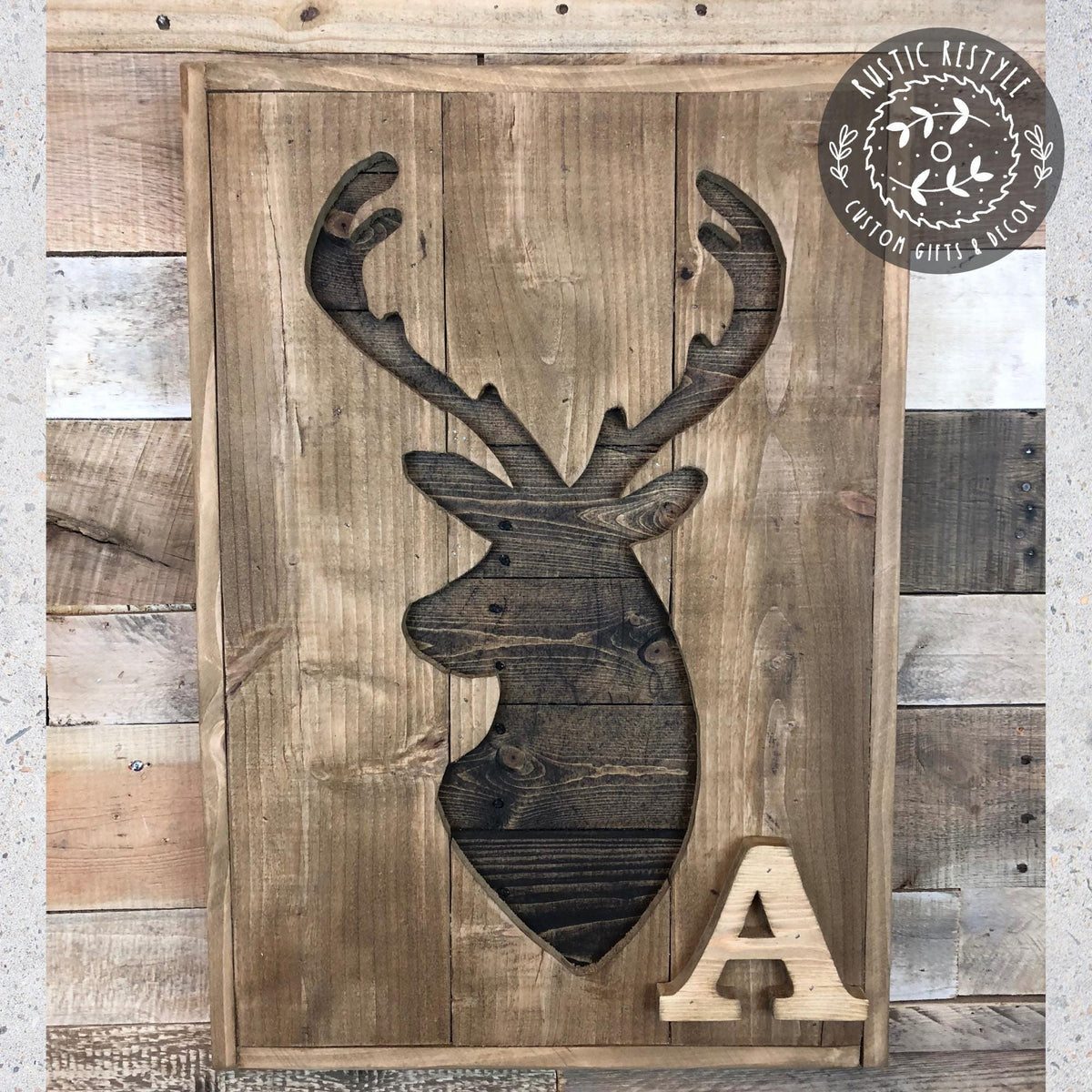 a wooden sign with a carved deer head and the letter "A" below it.