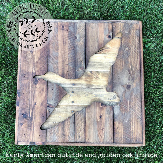 a wooden duck sculpture made from wooden planks, placed on a grassy surface.