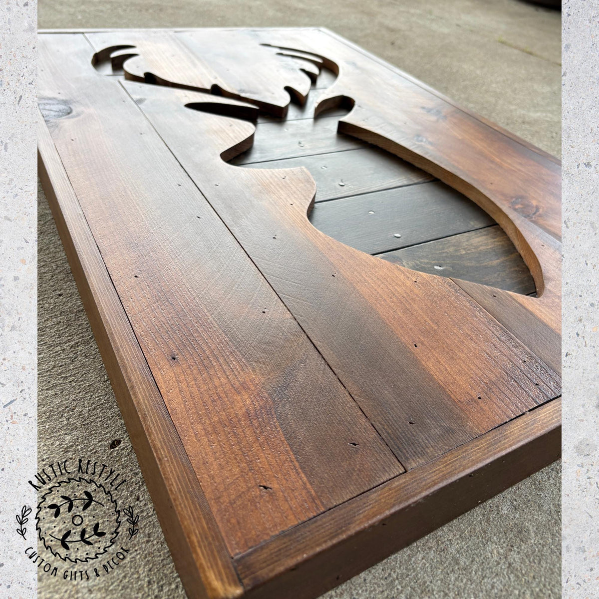 a wooden board with a carved deer head design on it.